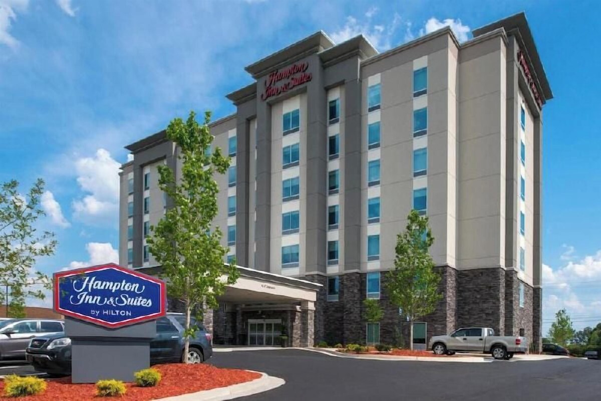 A Hampton Inn & Suites by Hilton building with a modern design, multiple floors, and a prominent entrance.