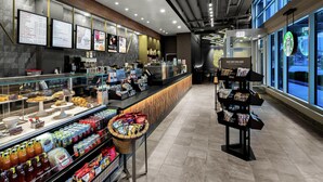 A modern coffee shop interior with a counter displaying pastries and a variety of beverages. - Hilton Garden Inn Chicago McCormick Place (Chicago)