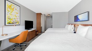 A hotel room with two beds, a desk with a TV, an orange chair, and artwork on the walls. - Hilton Garden Inn Chicago McCormick Place (Chicago)