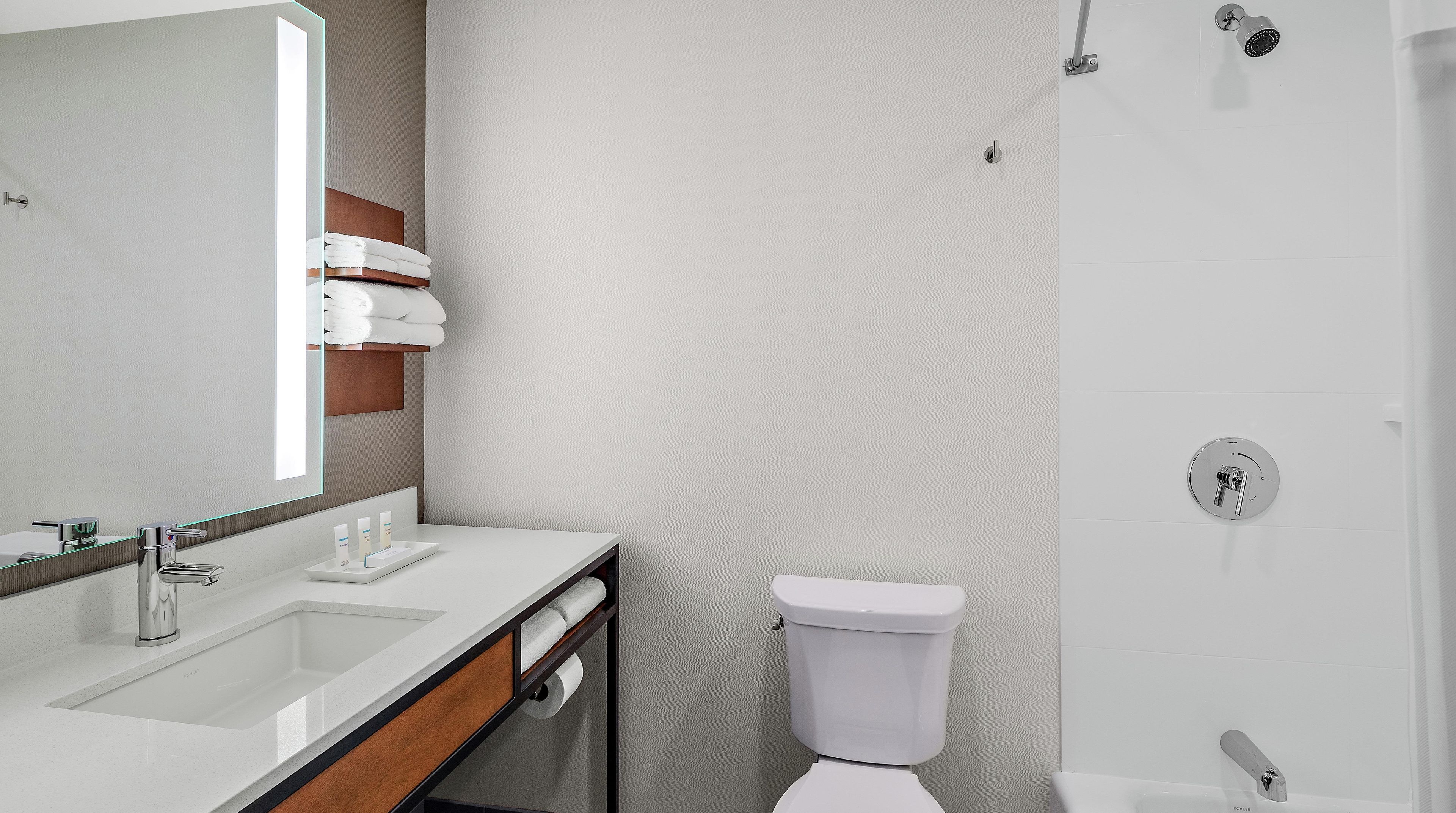 Uma casa de banho moderna com lavatório branco, espelho e sanita.