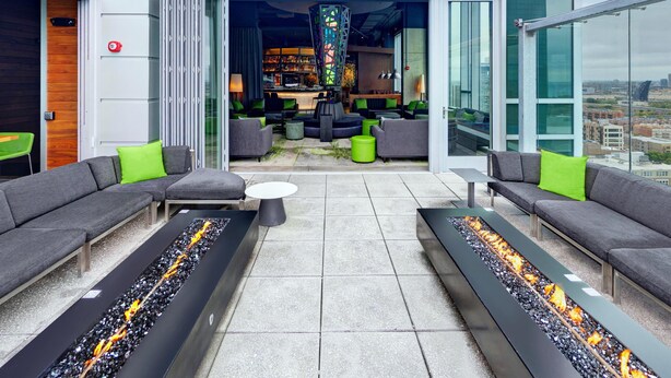 A modern lounge area with sofas, a bar, and a fire feature. - Hilton Garden Inn Chicago McCormick Place (Chicago)