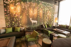 A modern lounge area with sofas, chairs, and a decorative wall featuring a deer and floral patterns. - Hilton Garden Inn Chicago McCormick Place (Chicago)