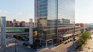 A modern high-rise building with a glass facade, located in an urban setting with a street and other buildings nearby. - Hilton Garden Inn Chicago McCormick Place (Chicago)