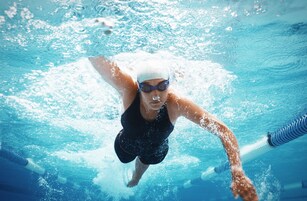 Nadador en una piscina con agua cristalina y marcas divisorias de carril.