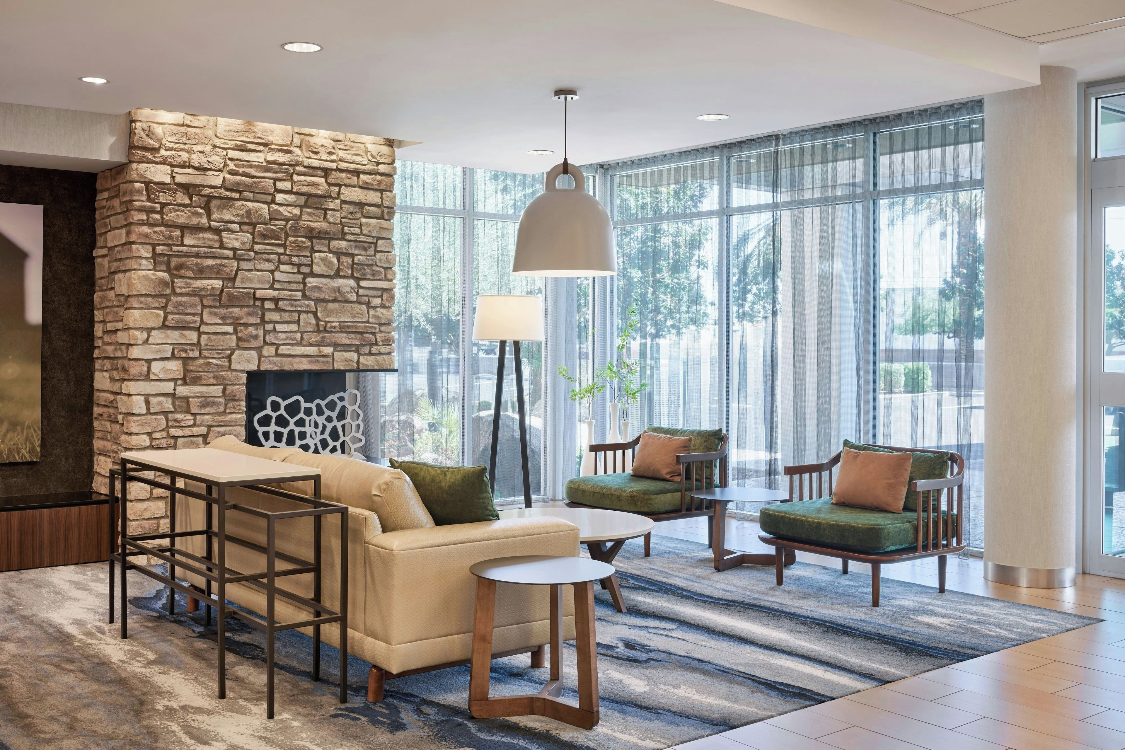 A modern lounge area with a stone accent wall, comfortable seating, and large windows.