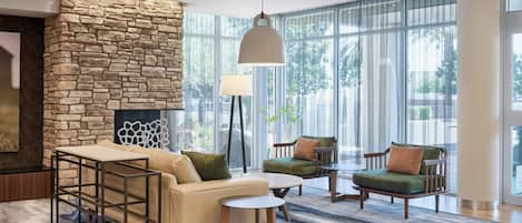 A modern lounge area with a stone accent wall, comfortable seating, and large windows.