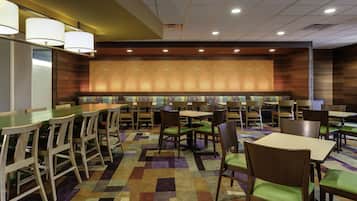 A restaurant with booths and tables, featuring patterned wallpaper and a checkered floor.