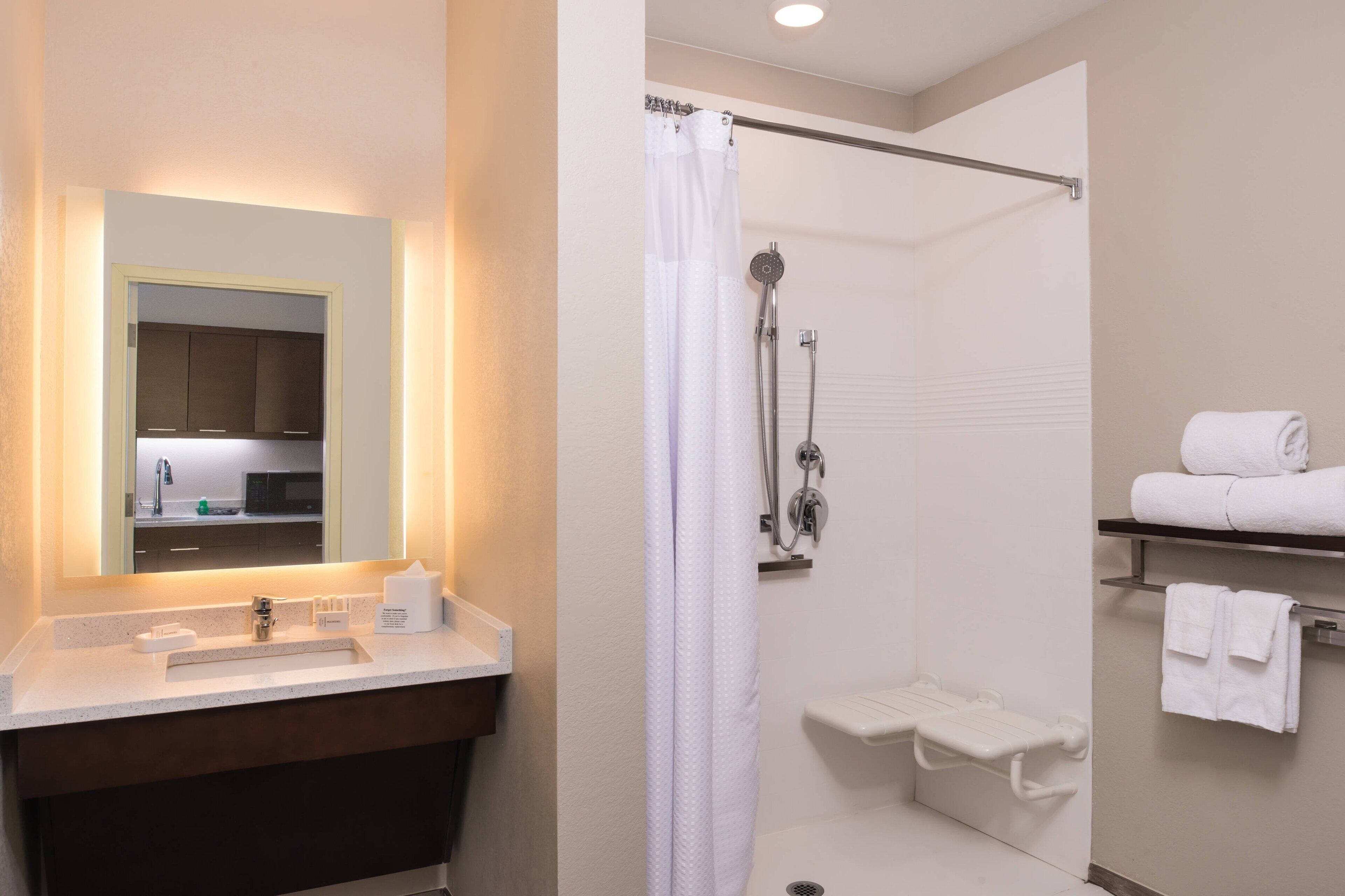 A modern bathroom with a sink, mirror, shower, and towel rack.
