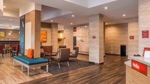 Un hall d’hôtel moderne avec un comptoir d’accueil, un espace salon et une carte affichée au mur.