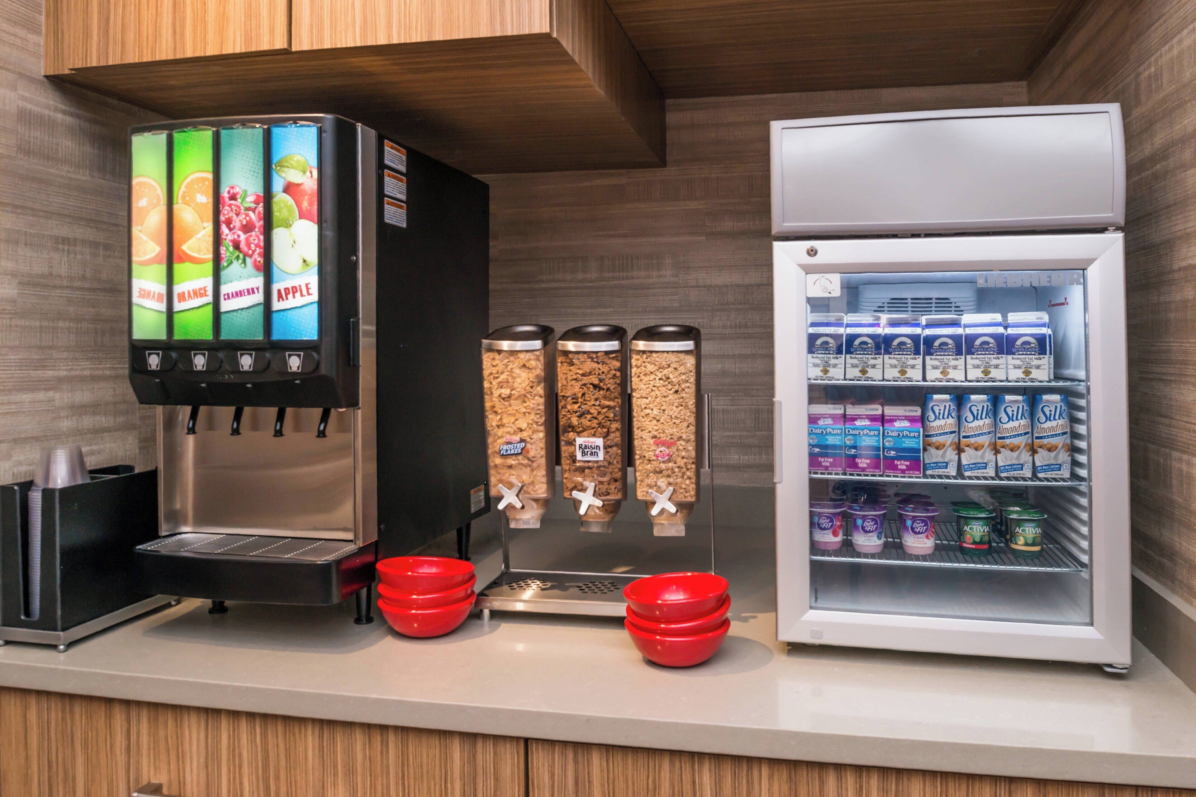 A self-service beverage station with a coffee machine and a refrigerated display of dairy products.