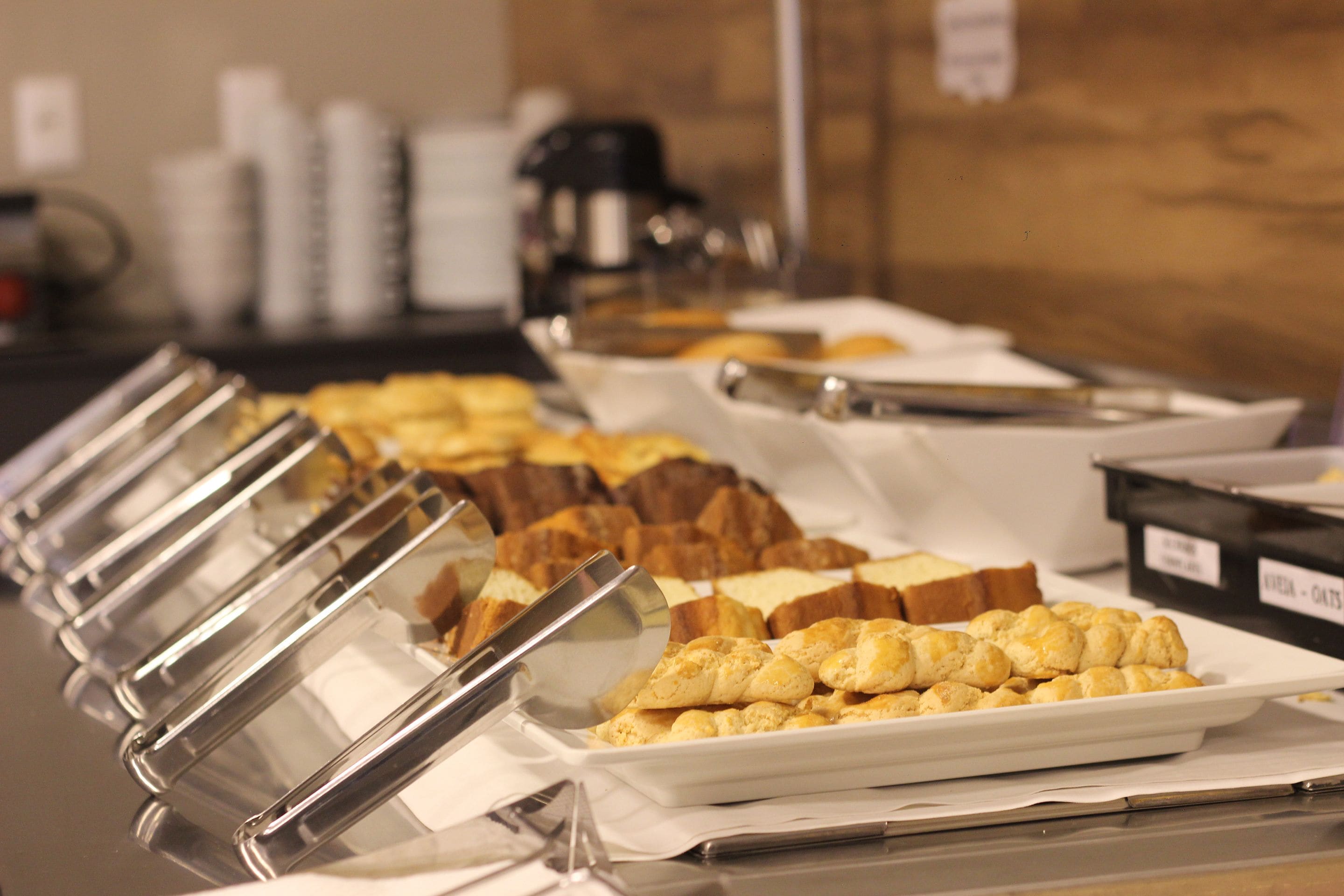 Un bufé con diversos alimentos, incluyendo pan, pasteles y una estación de café.