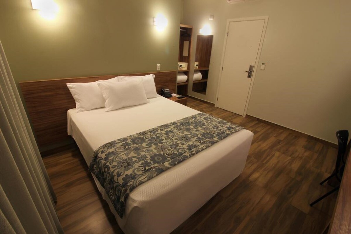 Una habitación de hotel con cama, mesita de noche y armario.