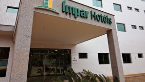 A hotel entrance with a tiled facade and a sign reading "Impar Hotels". - Ímpar Suítes Barão de Cocais (Barao de Cacais)