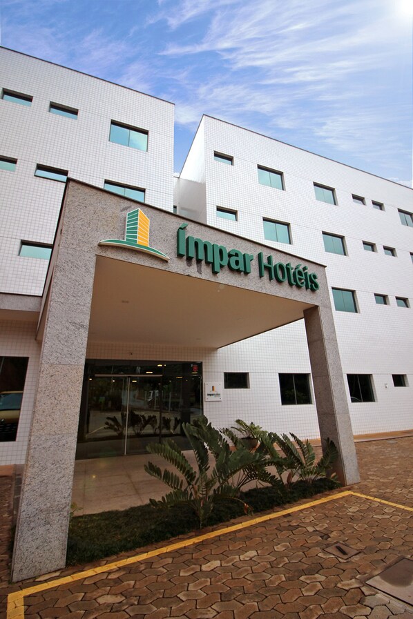 Entrada de un hotel con fachada de azulejos y un cartel que dice "Impar Hotels".