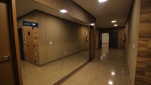 A hallway with a sign pointing to the 'Academia' and 'Fitness Center'. - Ímpar Suítes Barão de Cocais (Barao de Cacais)