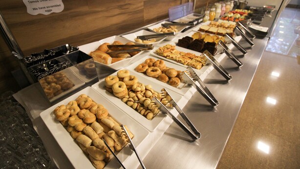 A buffet with various food items and utensils. - Ímpar Suítes Barão de Cocais (Barao de Cacais)