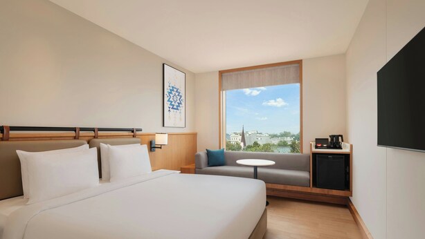 A hotel room with a large bed, a sofa, a small table, and a TV. - Fairfield by Marriott Amritsar (Amritsar)