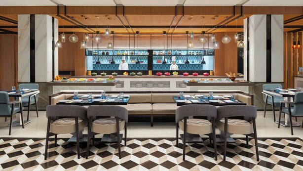 A modern restaurant with a central bar area, multiple seating options, and a patterned floor. - Fairfield by Marriott Amritsar (Amritsar)
