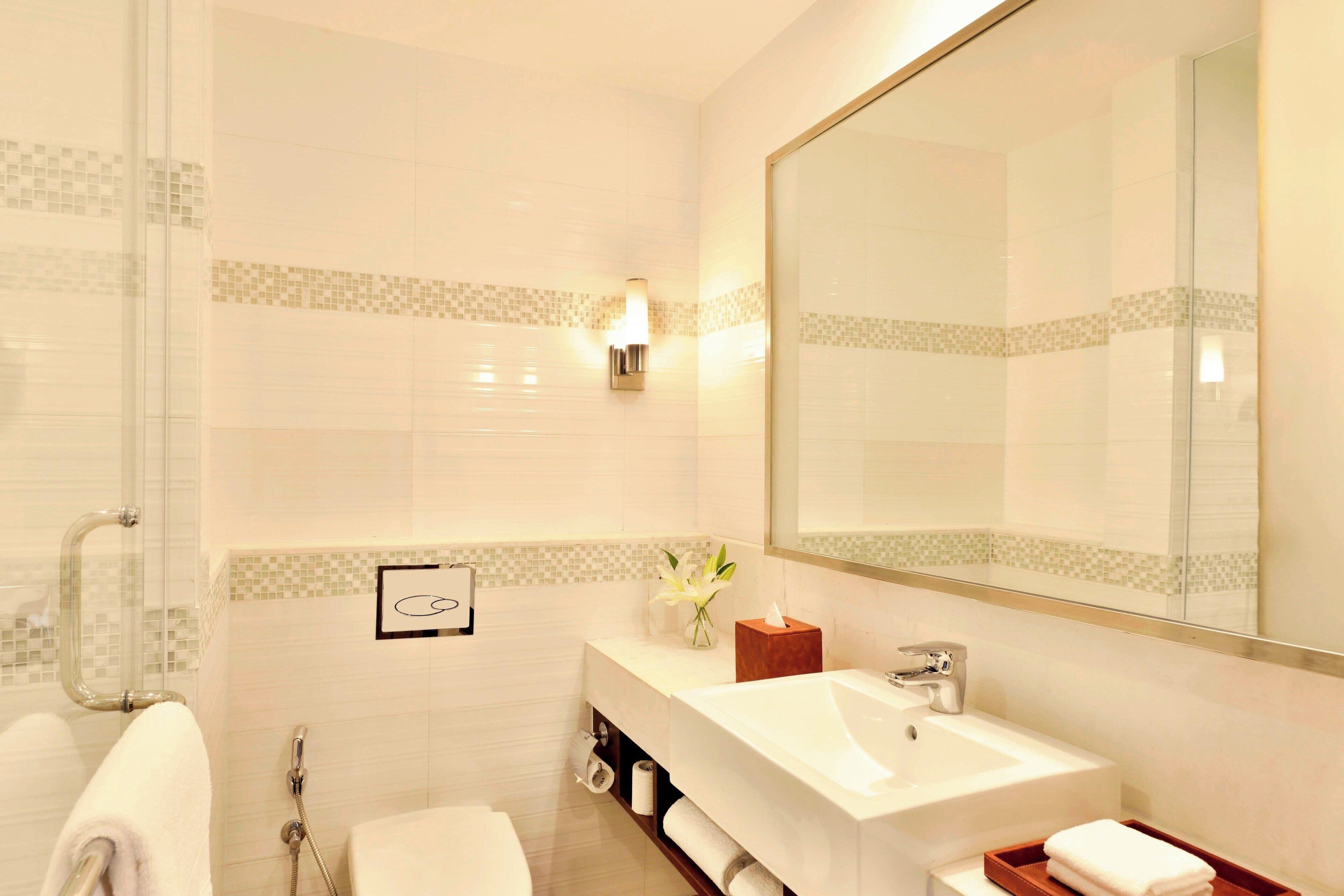 A modern bathroom with a large mirror, a sink, and a shower.
