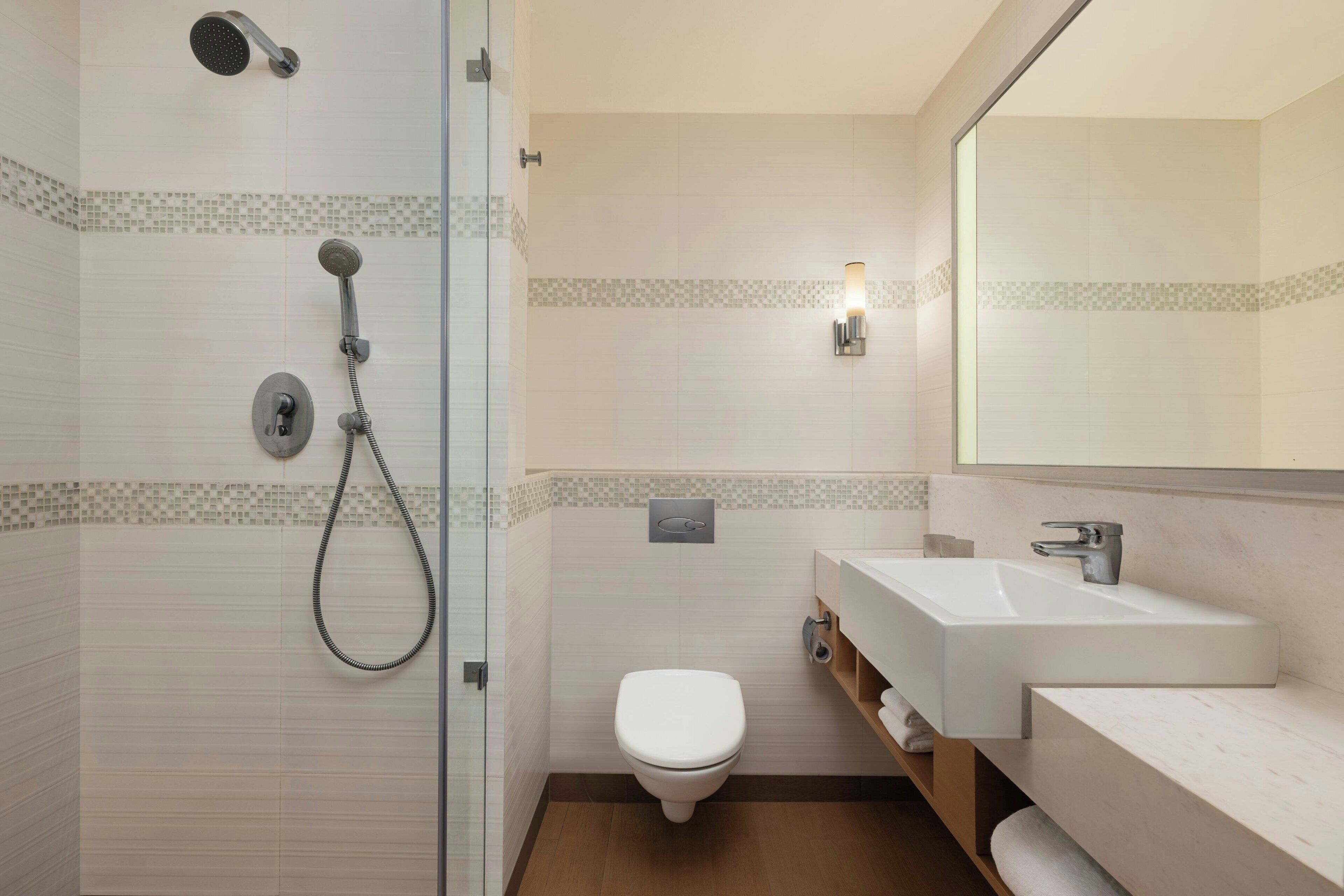 Un baño moderno con cabina de ducha de vidrio, inodoro y lavabo con espejo.