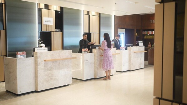 A hotel reception area with marble reception desks, a modern interior design, and a visible sign for the Marriott Bonvoy hotel.