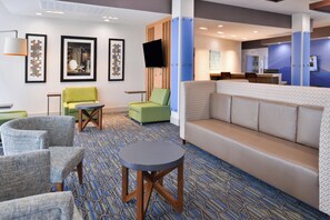 A hotel lobby with seating, artwork, a flat-screen TV, and a reception desk. - Holiday Inn Express Early by IHG (Early)