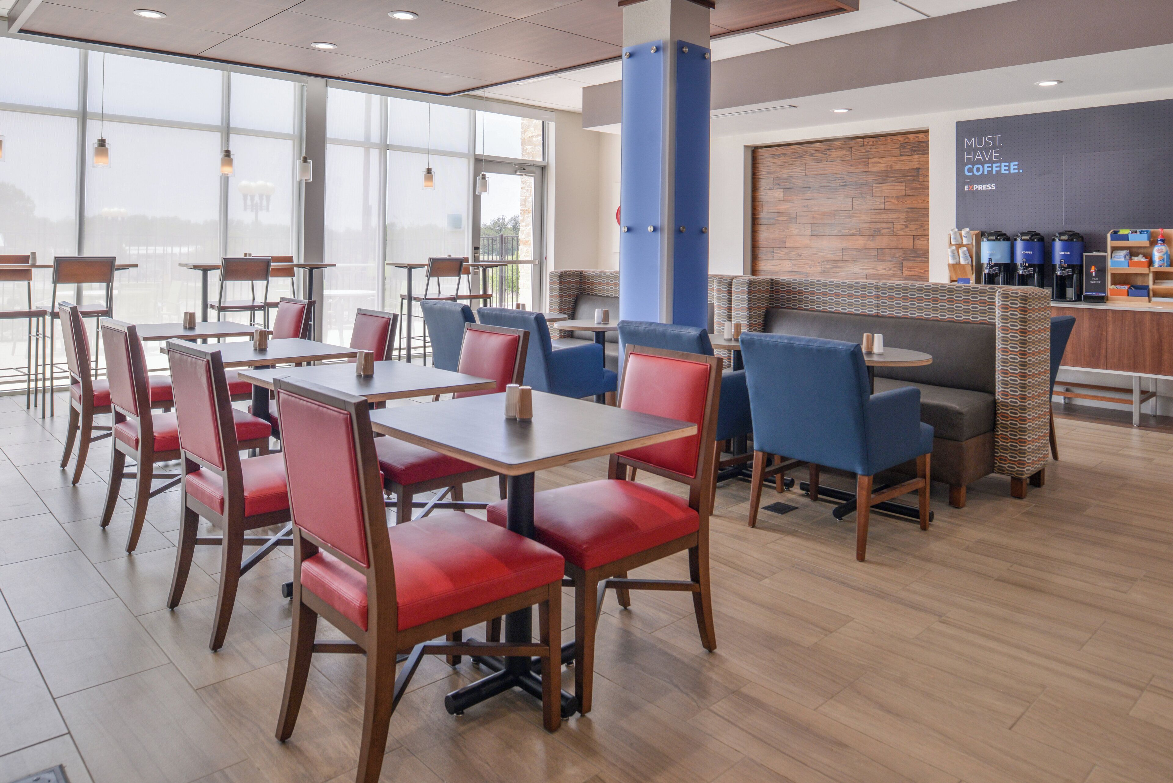 Een modern café interieur met houten tafels en stoelen, een koffiebar en grote ramen.