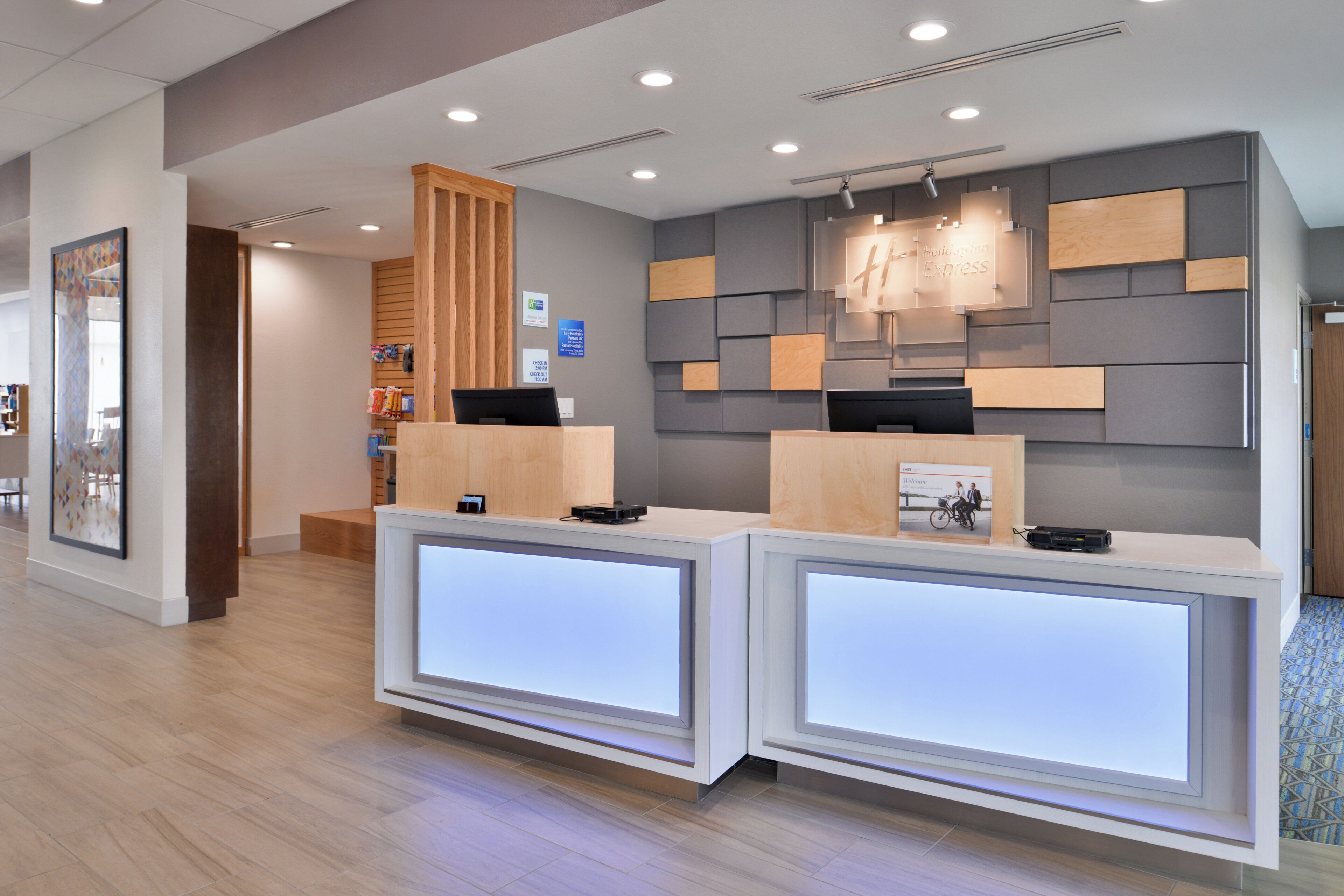 Una recepción con diseño moderno, un mostrador de recepción y un panel informativo de pared.