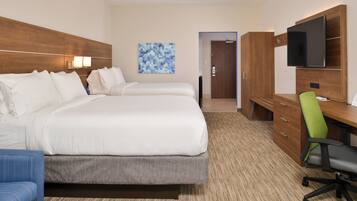 A hotel room with two beds, a desk, a chair, a television, and a door leading to a bathroom.