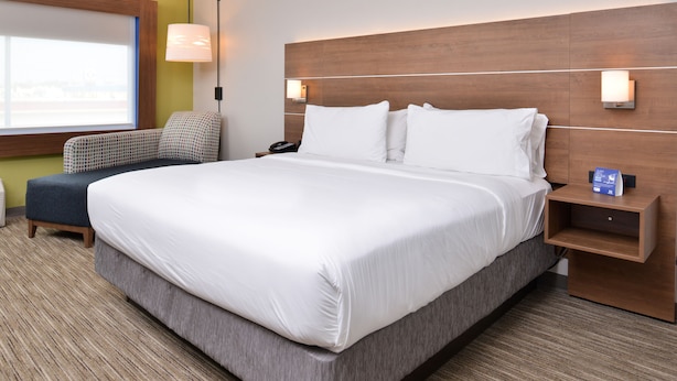 A hotel room with a large bed, a bedside table, a lamp, and a view of the outside. - Holiday Inn Express Early by IHG (Early)