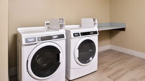 Two front-loading washing machines with control panels, a shelf above them, and a tiled floor. - Holiday Inn Express Early by IHG (Early)