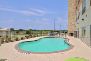 A swimming pool with a curved edge, surrounded by a paved deck and a metal fence. - Holiday Inn Express Early by IHG (Early)