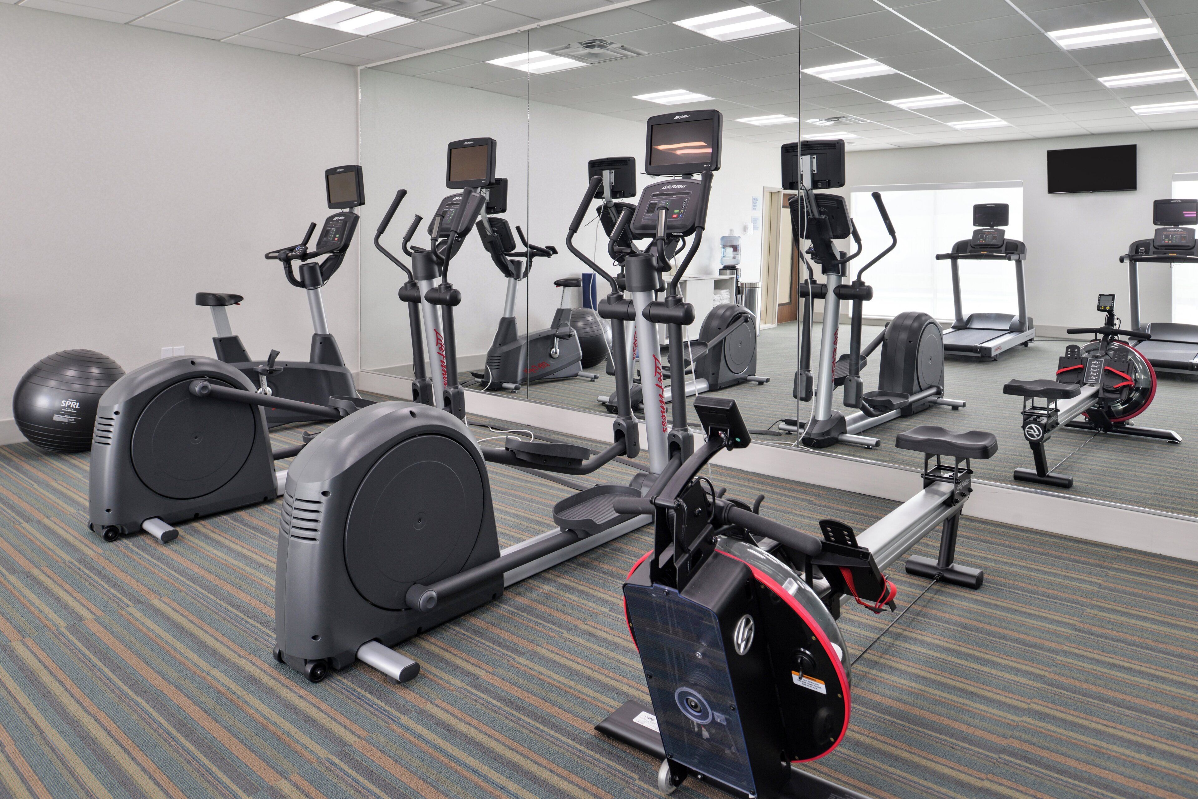 Ein Fitnessraum mit unterschiedlichen Trainingsgeräten, darunter Laufbänder, Ergometer und Crosstrainer.