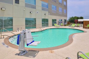 A swimming pool with a lifeguard stand, lounge chairs, and a building with large windows in the background. - Holiday Inn Express Early by IHG (Early)