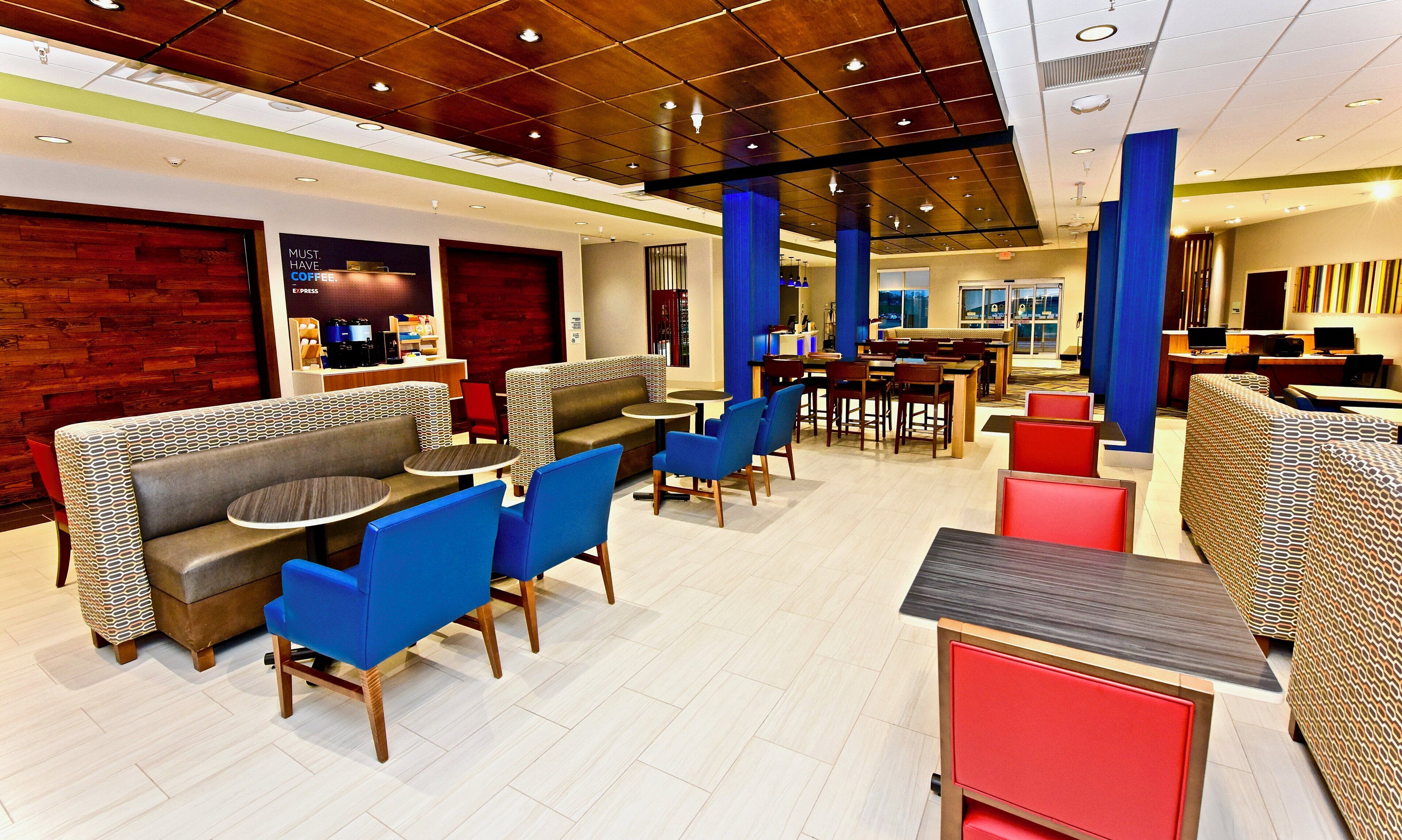 Um hall de hotel moderno com áreas de estar, um café e um espaço para refeições.