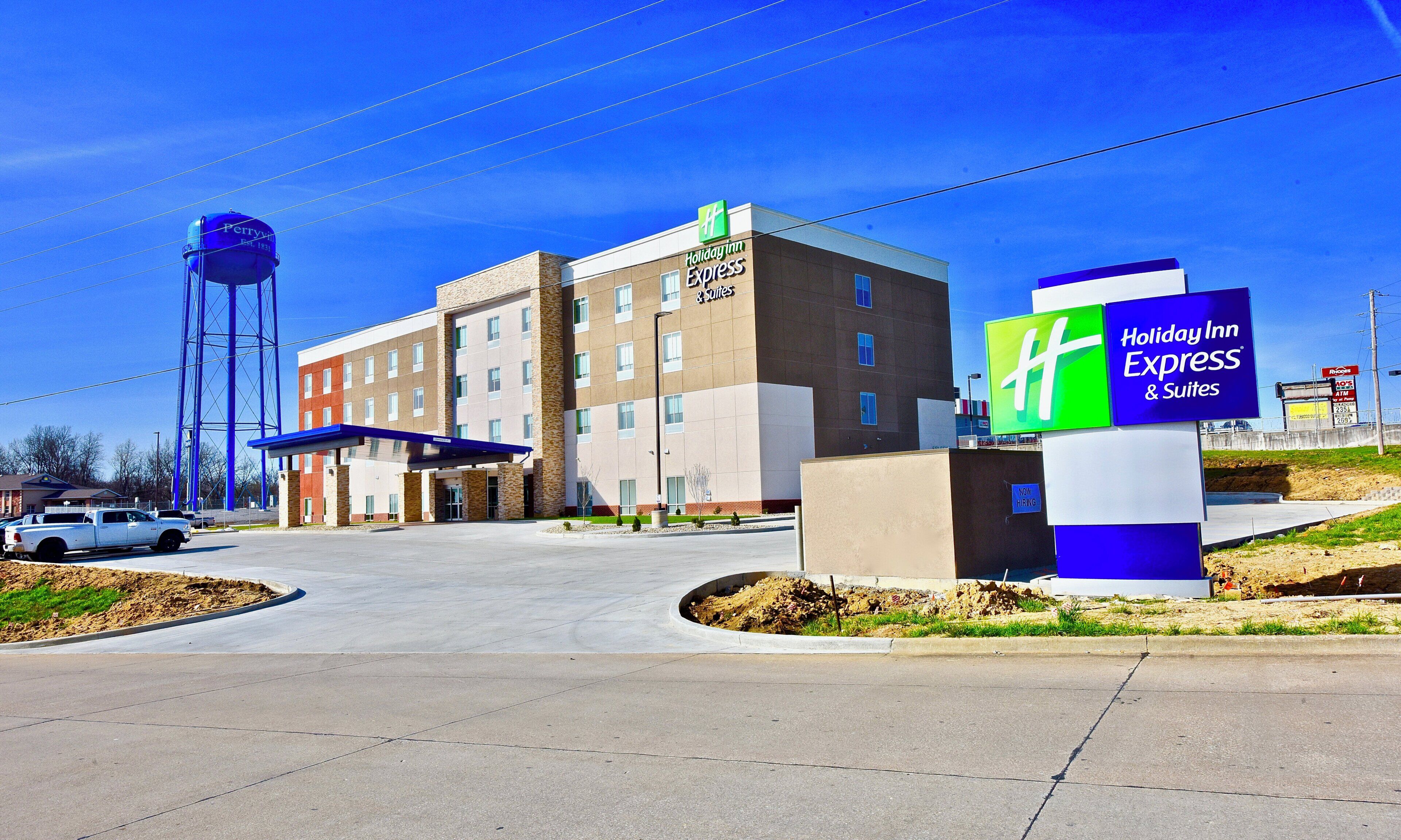 A Holiday Inn Express hotel with a clear sky, a water tower, and a parking area.