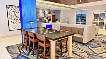 A hotel lobby with a reception desk, seating area, and a patterned carpet.