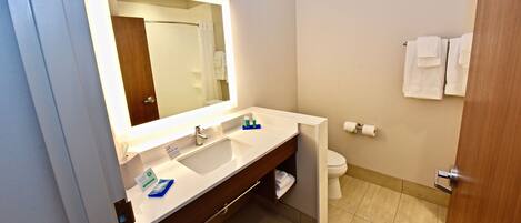 A bathroom with a large mirror, a sink, a toilet, and a towel rack.