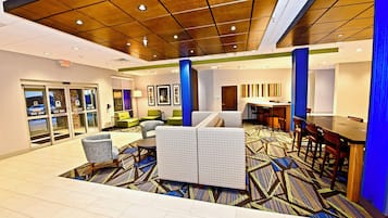 Un vestíbulo de hotel con una zona de estar, un mostrador de recepción y un bar.