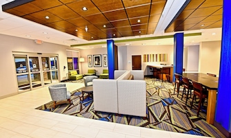 A hotel lobby with a seating area, a reception desk, and a bar.