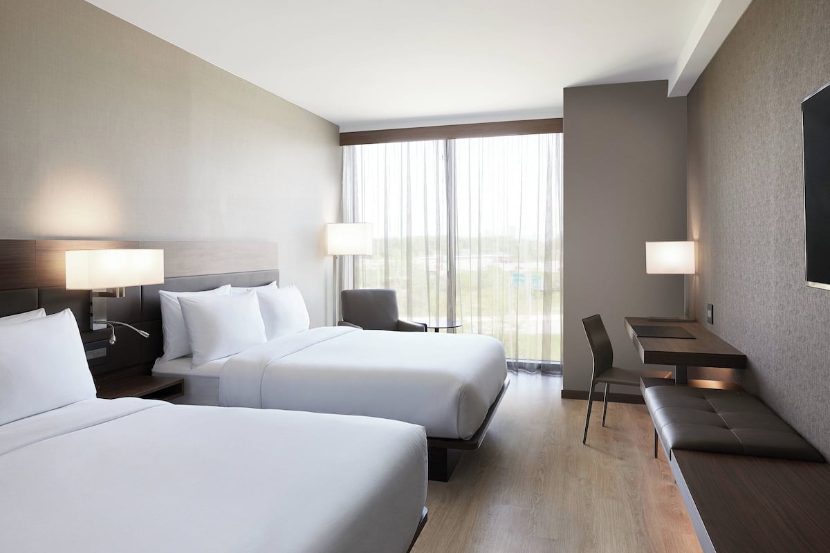A hotel room with two beds, a desk, and a chair.