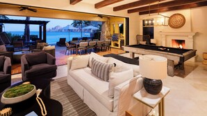 A spacious living area with a sofa, chairs, a pool table, and a fireplace.