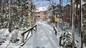 A snow-covered ski trail with wooden railings and signs indicating a slow area and no jumping allowed. - Trail Creek: Ski home to renovated 1st floor, 1br condo. Sleeps 4. (Killington)