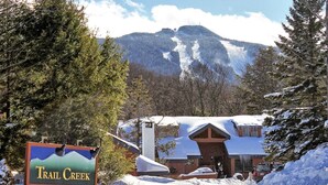 A snow-covered building with a sign reading "Trail Creek." - Trail Creek: Ski home to renovated 1st floor, 1br condo. Sleeps 4. (Killington)
