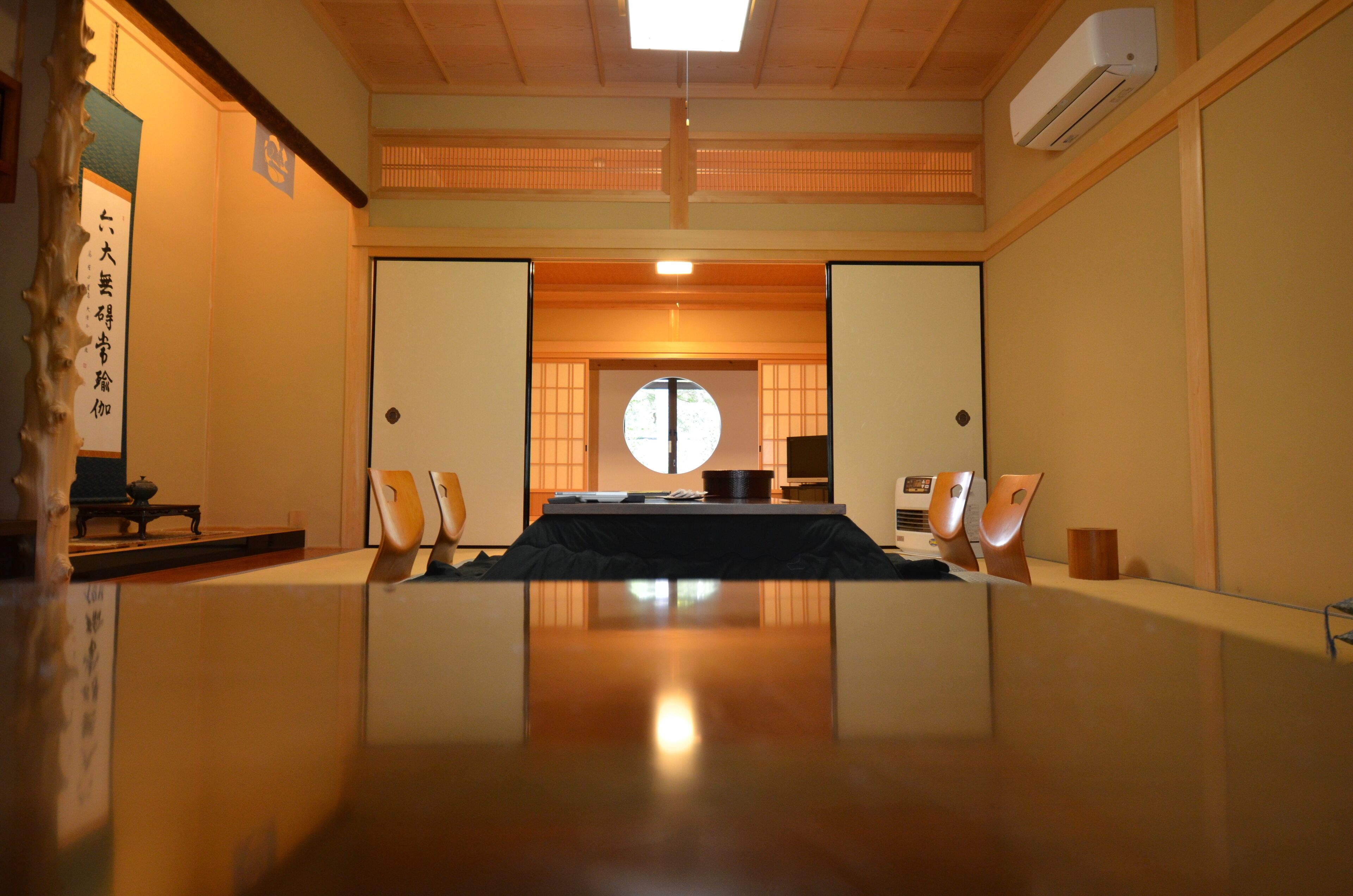 A traditional Japanese room with tatami flooring, a tatami mat table, a low table, and a shoji screen door.