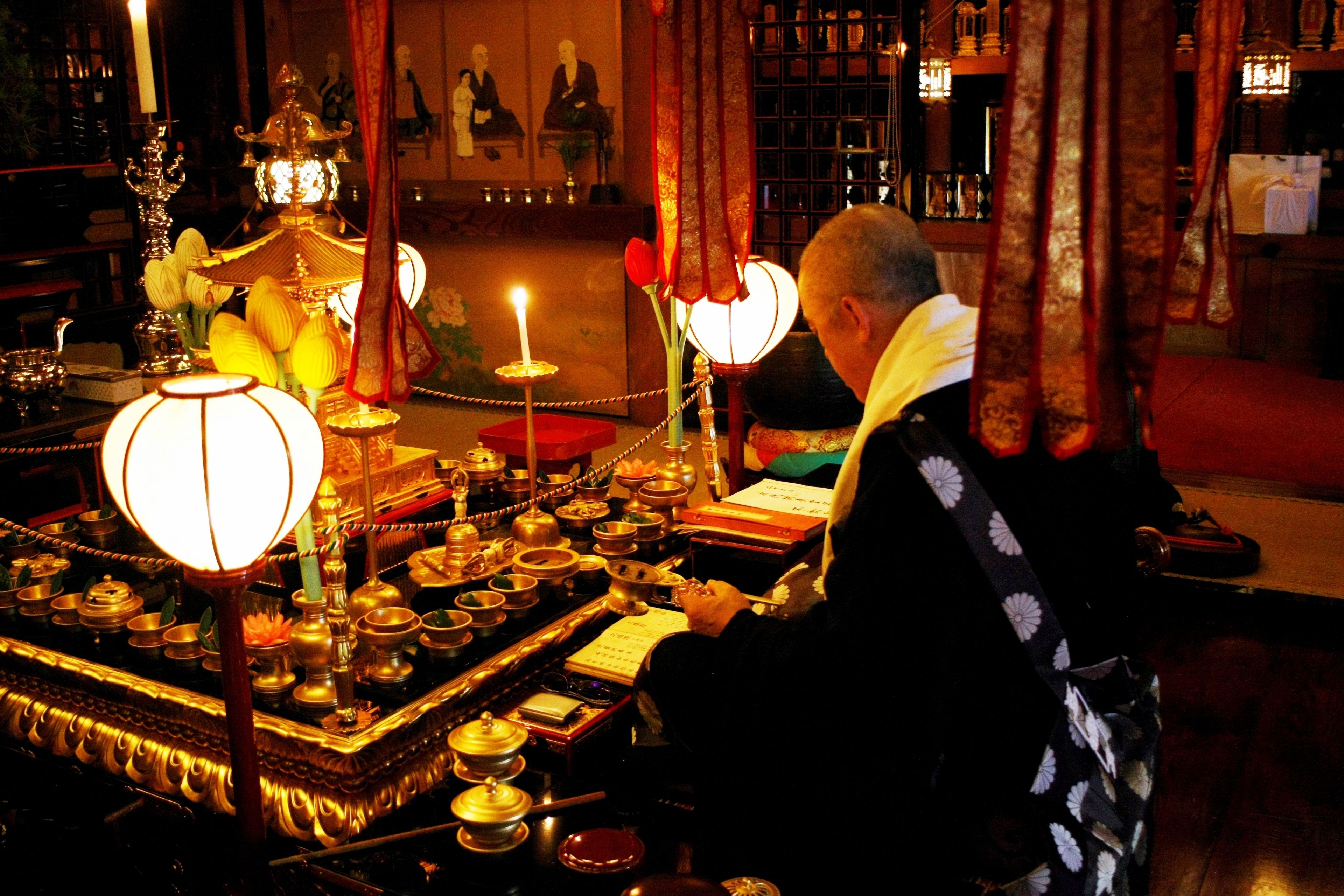 A room with a traditional altar, lit candles, and various ritual items.