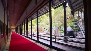 A corridor with a red carpet leading to a view of a garden with rocks and trees. - Koyasan Syukubou Fudouin (Koya)