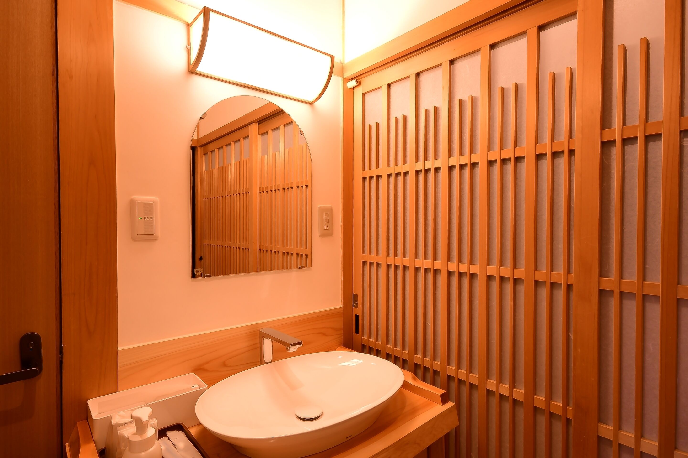 Ein Badezimmer mit einem Holzkosmetikschrank, einem Waschbecken, einem Spiegel und einer Toilette.