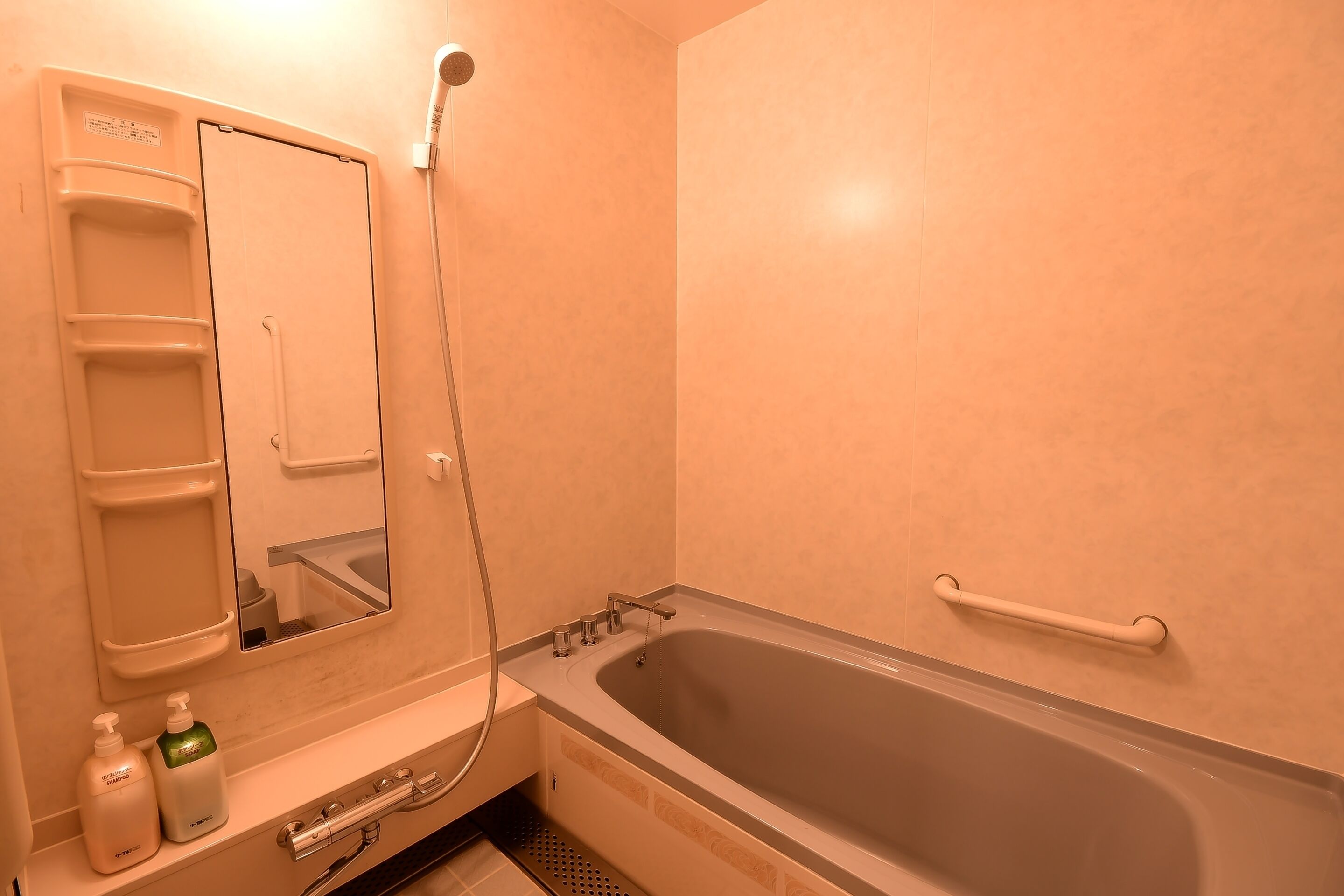Un baño con bañera, ducha, lavamanos con espejo y toallero.