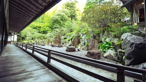 A wooden walkway with a railing, surrounded by rocks and greenery. - Koyasan Syukubou Fudouin (Koya)